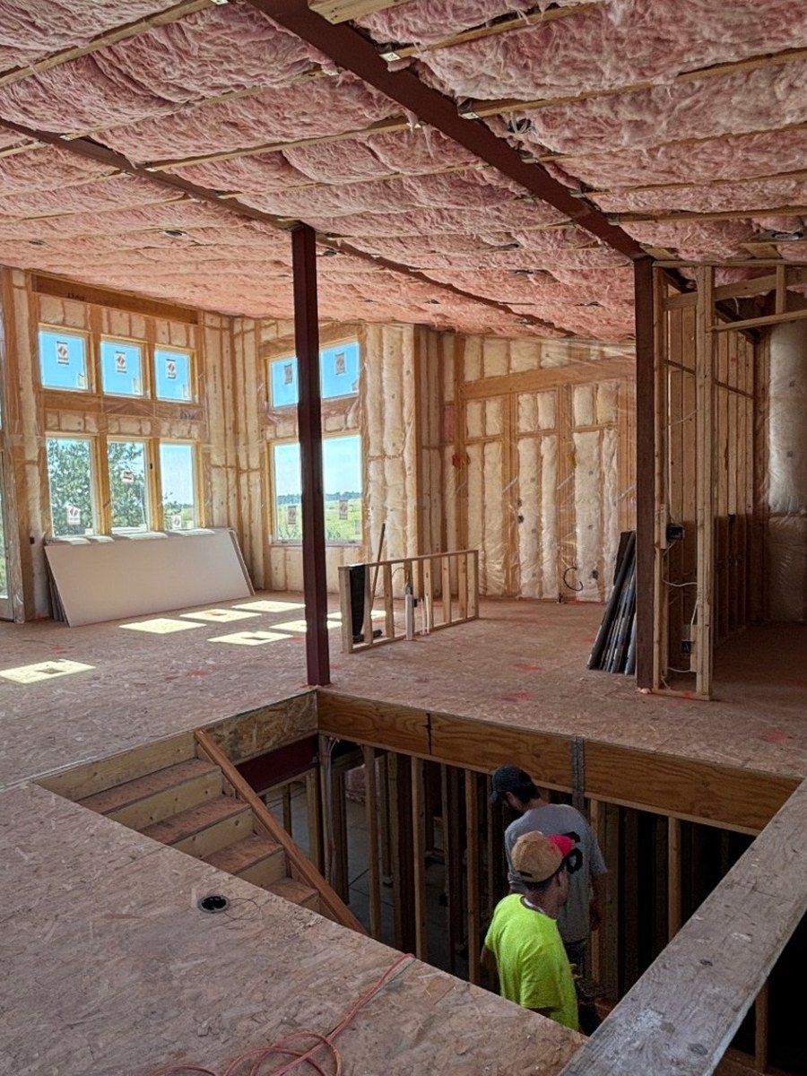 Great room under construction: wood framing, a steel column and insulation batts installed in the ceiling
