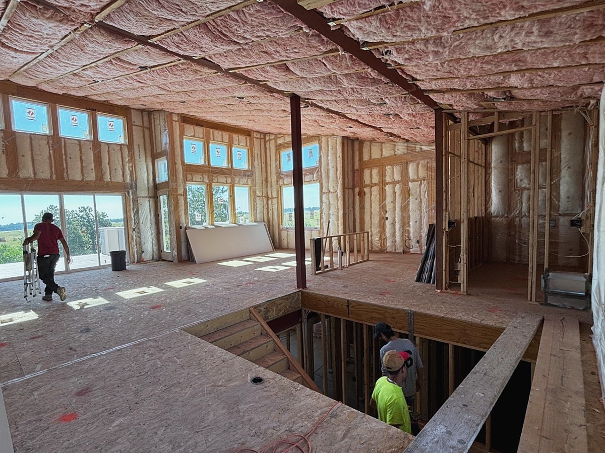 Great room with insulation batts in the ceiling and wood framing in place, before drywall