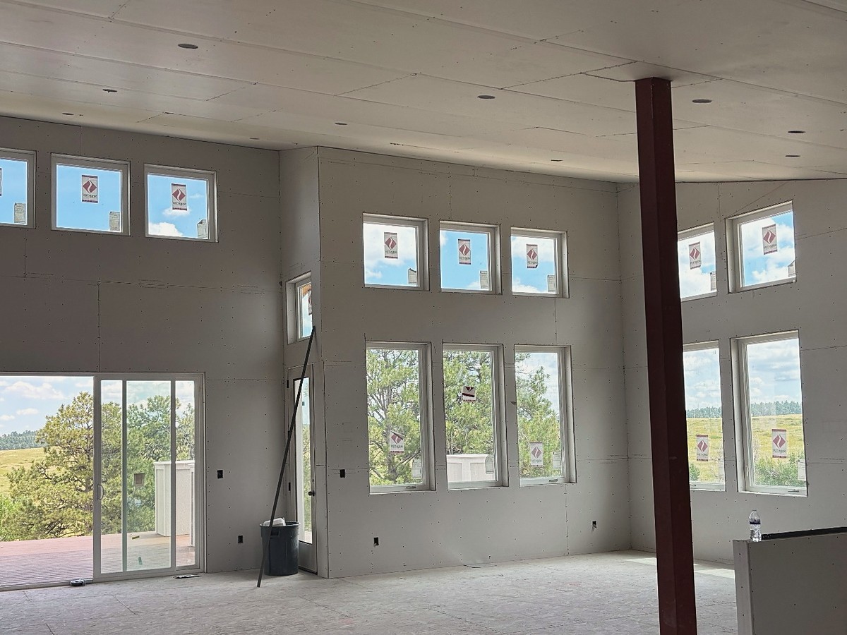 The same great room with drywall panels hung on the ceiling and walls, ready for taping and finishing