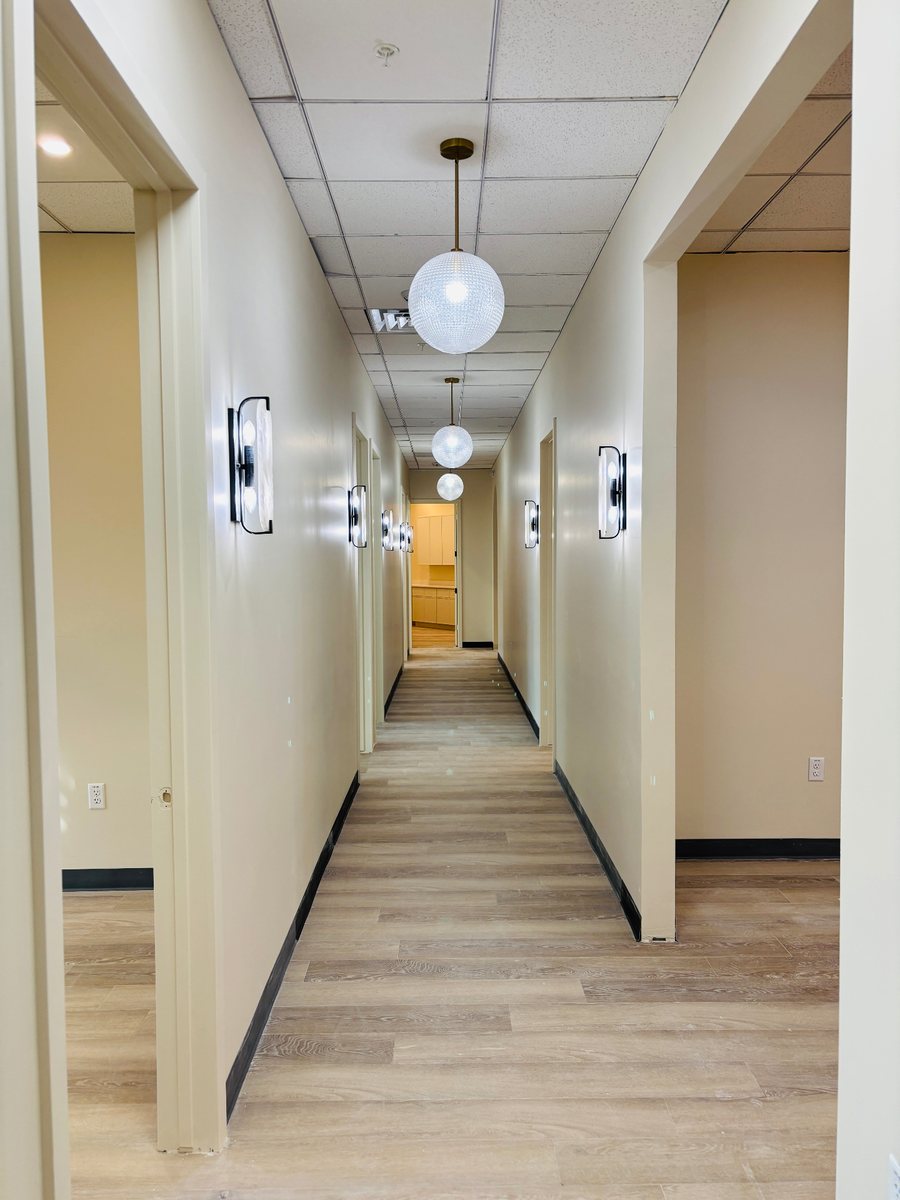Finished corridor with drywall, baseboards, wood-look flooring and lighting
